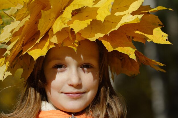 Young girl with diadem from yellow maple leaves at the park