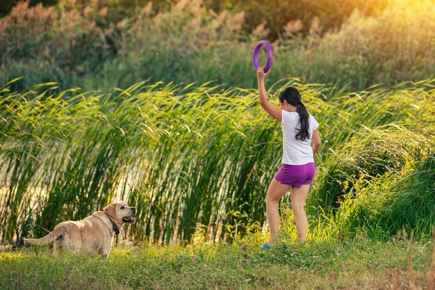 A young girl with a dog plays by the lake Girl holding a ring