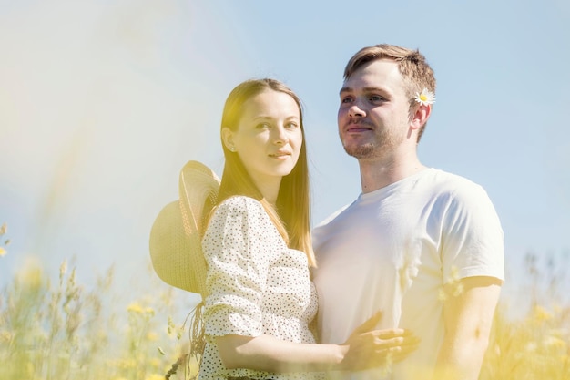 Young girl with a guy in a field on a bright sunny day Love and tenderness Great summer vacation in nature