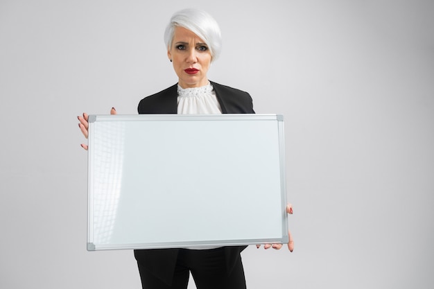 Young girl with a magnetic Board in her hands stands isolated on a light background