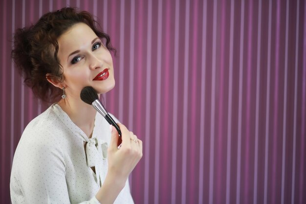 Young girl with a make-up artist in the studio in front of a mirror