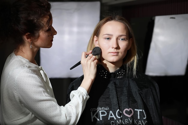 Young girl with a makeup artist in the studio in front of a mirrorxA