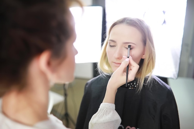 Young girl with a makeup artist in the studio in front of a mirrorxA