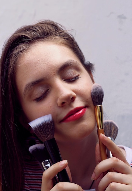 Young girl with makeup brushes portrait of a teenager with problem skin on a white background