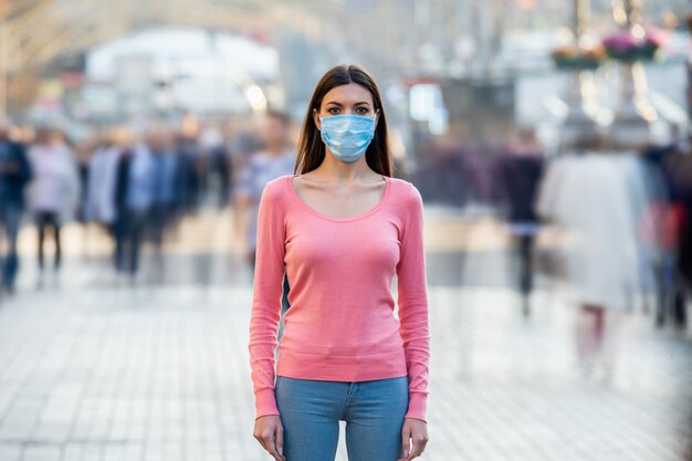 Photo the young girl with medical mask on her face stands on the crowded street