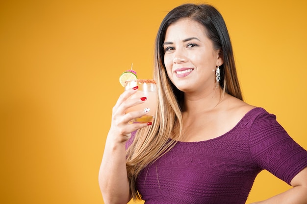 Young girl with refreshing drink in hand in red studio