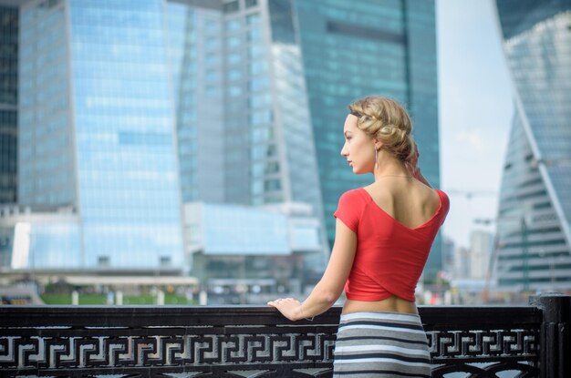 A young girl with a short haircut in a red Tshirt stands on the pier overlooking the city The concept of space