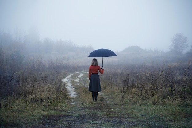 Young girl with umbrella in autumn field