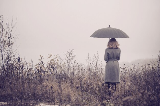 Photo young girl with umbrella in autumn field