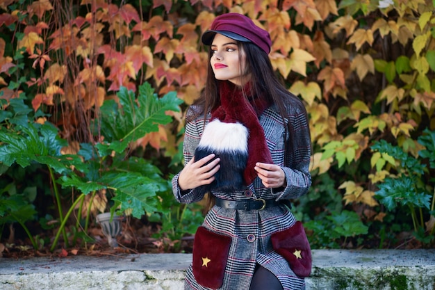 Young girl with very long hair smiling and wearing winter coat and cap in autumn leaves background