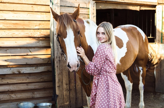 A young girl woman hugs her horse in the stable