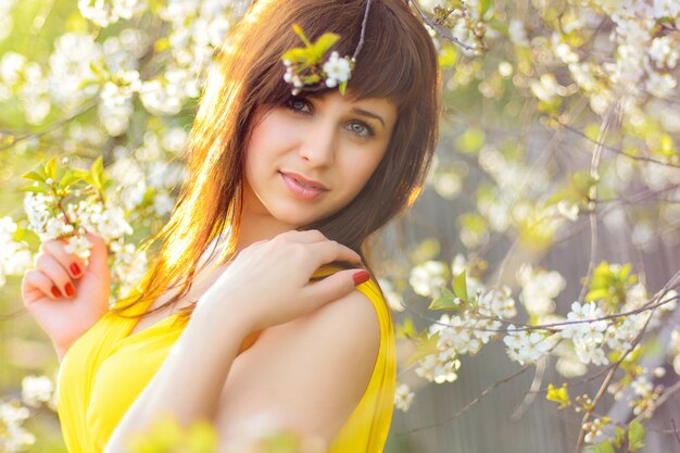 Young girl in yellow dress in spring on cherry blossom