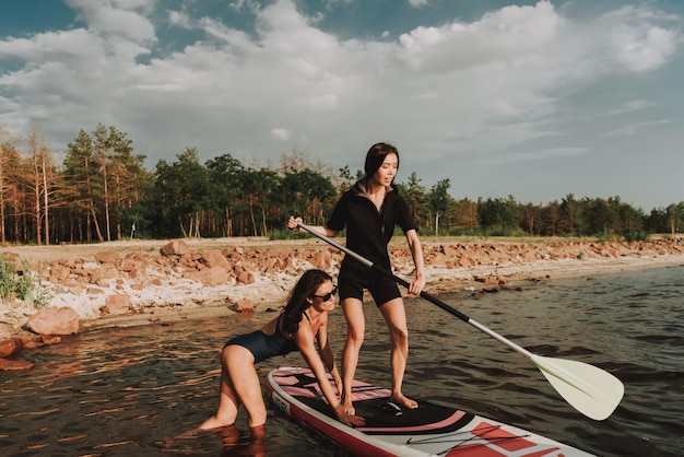 Young Girls In Wetsuit Rowing Surf With Paddle.