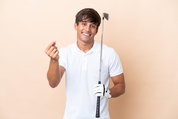 Photo young golfer player man isolated on ocher background making money gesture