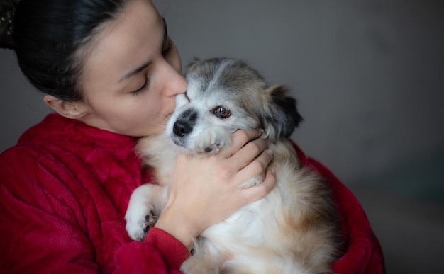 Young gorgeous woman with her cute little fluffy dog on hands at home Pet concept