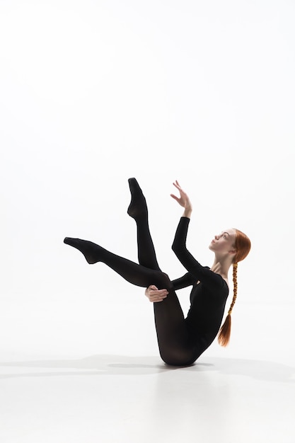 Young and graceful ballet dancer in minimal black style isolated on white studio background