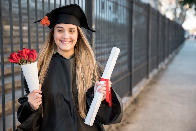 Young graduate with bouquet of roses