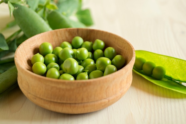 Young green peas on white wooden surface