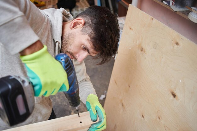 Young guy doing repairs in the apartment work with wood