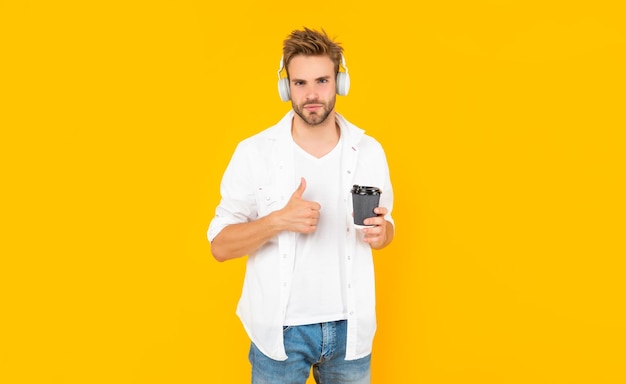 Young guy in headphones drink coffee music lover listen to music wireless device accessory