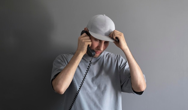 A young guy holding a handset and making a phone call using a vintage telephone