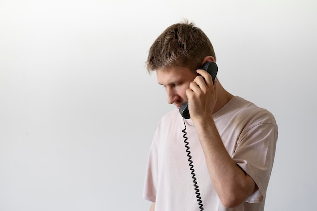 A young guy holding a handset and making a phone call using a vintage telephone