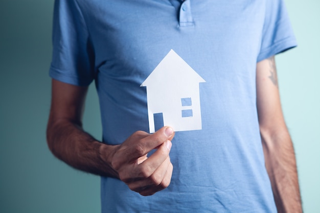 A young guy holding a house in his hand