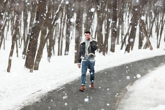 A young guy holding a phone winter background