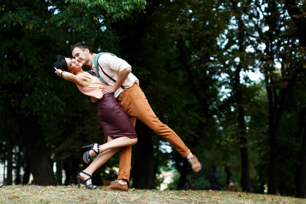 Young guy holds his lover by the waist, the girl is happy with a smile on his face