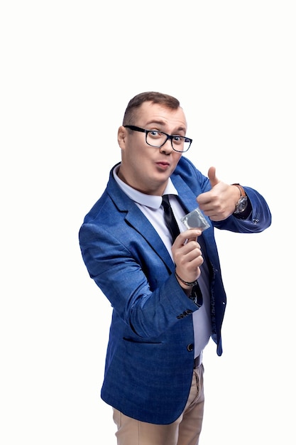 Young guy in a jacket bow tie glasses holds a condom in his hand isolated on white background