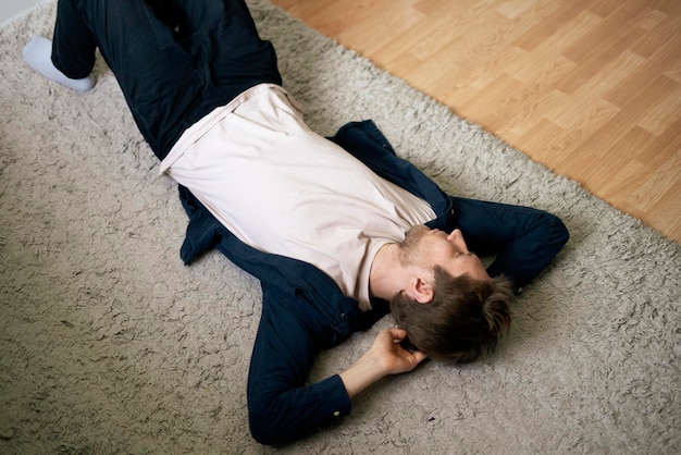 Photo a young guy lying on the floor on the carpet at home