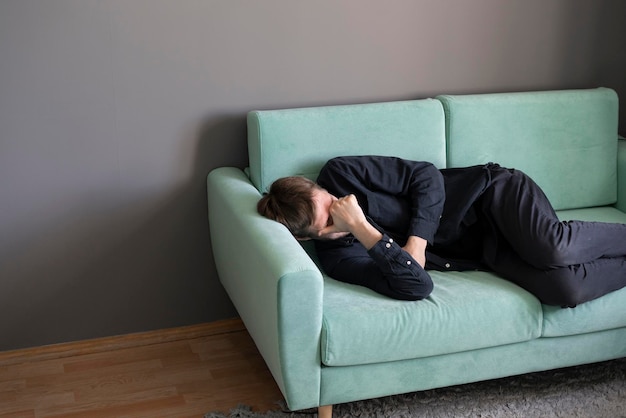 A young guy lying and sleeping on the sofa at home in the afternoon