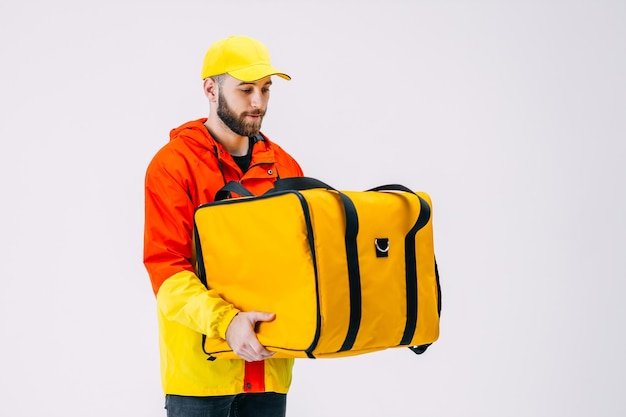 A young guy moonlights as a courier after school he holds a yellow thermal bag waiting for an order