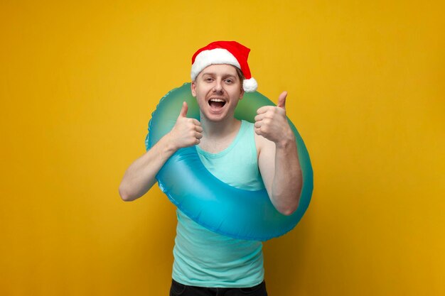 Photo young guy in a new year's hat in the summer on vacation with an inflatable swim ring rejoices