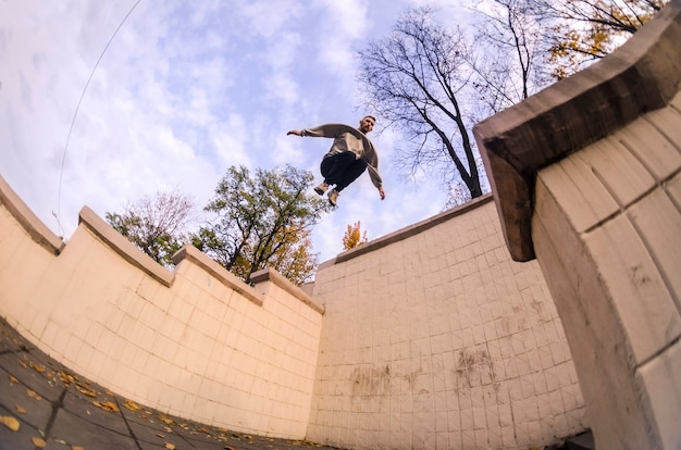 A young guy performs a jump through the space between the concrete parapets. 