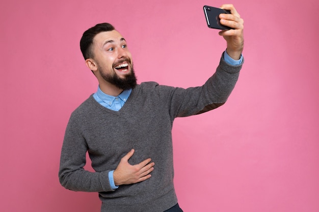 young guy on a pink background takes a selfie