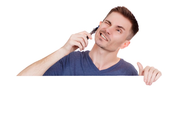 Young guy shaves his face with a razor on a white background. Handsome men are shave and beard. Copy Space.