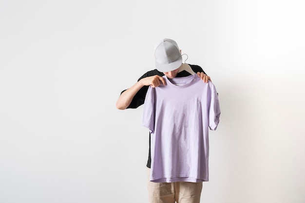 A young guy trying on new clothes isolated on pastel background