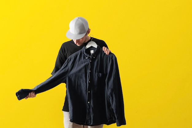 A young guy trying on new clothes isolated on pastel background