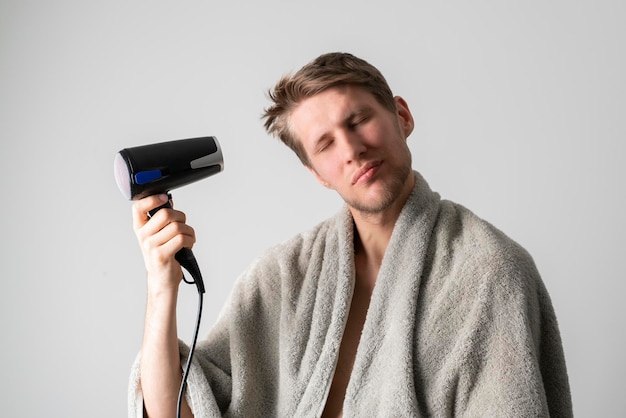 A young guy using hair dryer daily morning routine