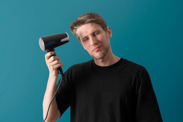 A young guy using hair dryer daily morning routine