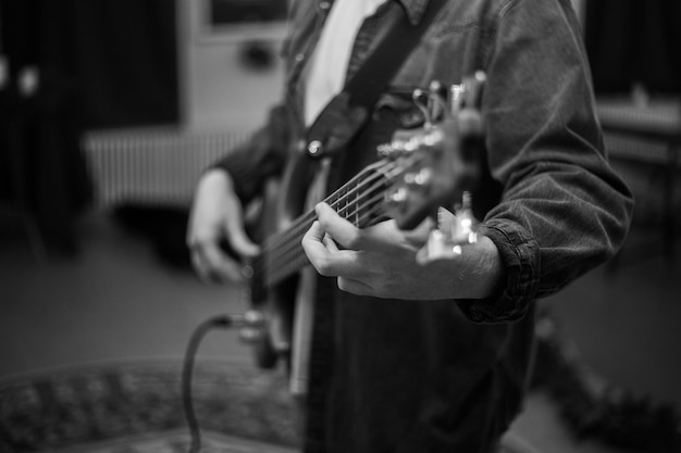 A young guy with a beard plays a bass guitar with five strings