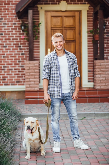 Young guy with retriever walking near the house