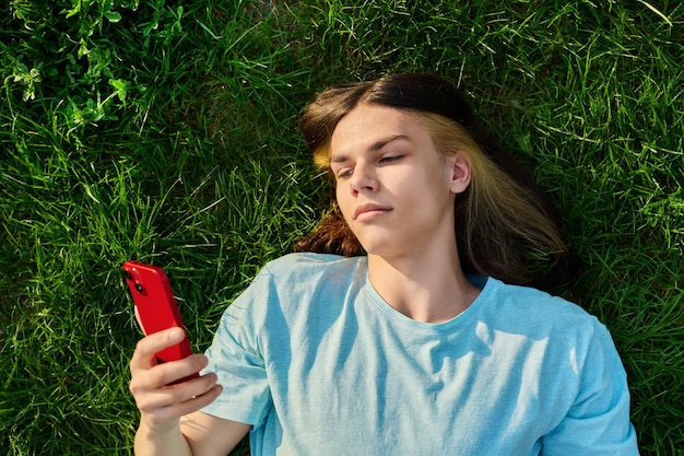 Young guy with smartphone in his hands on green grassy background