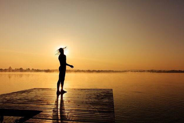 Young guy with strong muscles standing on wooden pier