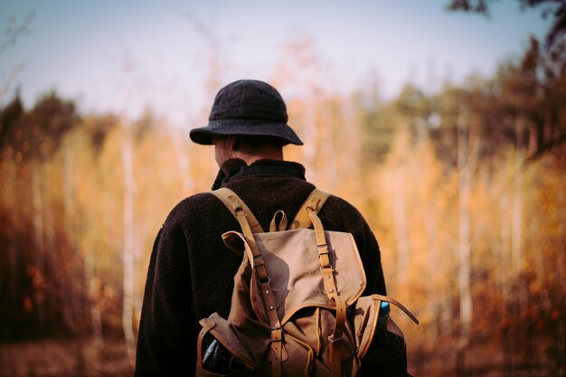 Young guy with a vintage backpack in the forest.