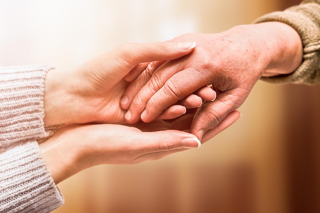 Young hand holds hand of senior, care and help concept