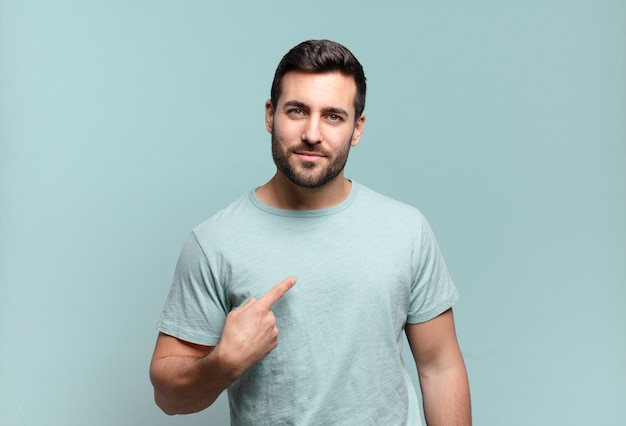 Young handsome adult man looking proud, confident and happy, smiling and pointing to self or making number one sign