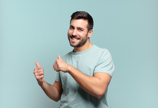 Young handsome adult man smiling cheerfully and casually pointing to copy space on the side, feeling happy and satisfied