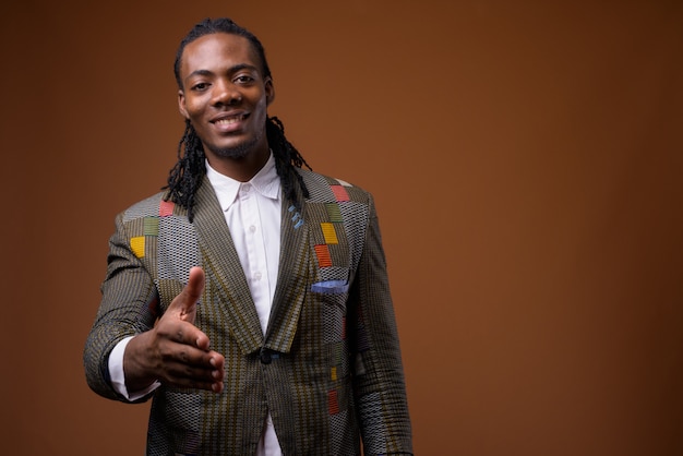 Young handsome African businessman against brown background